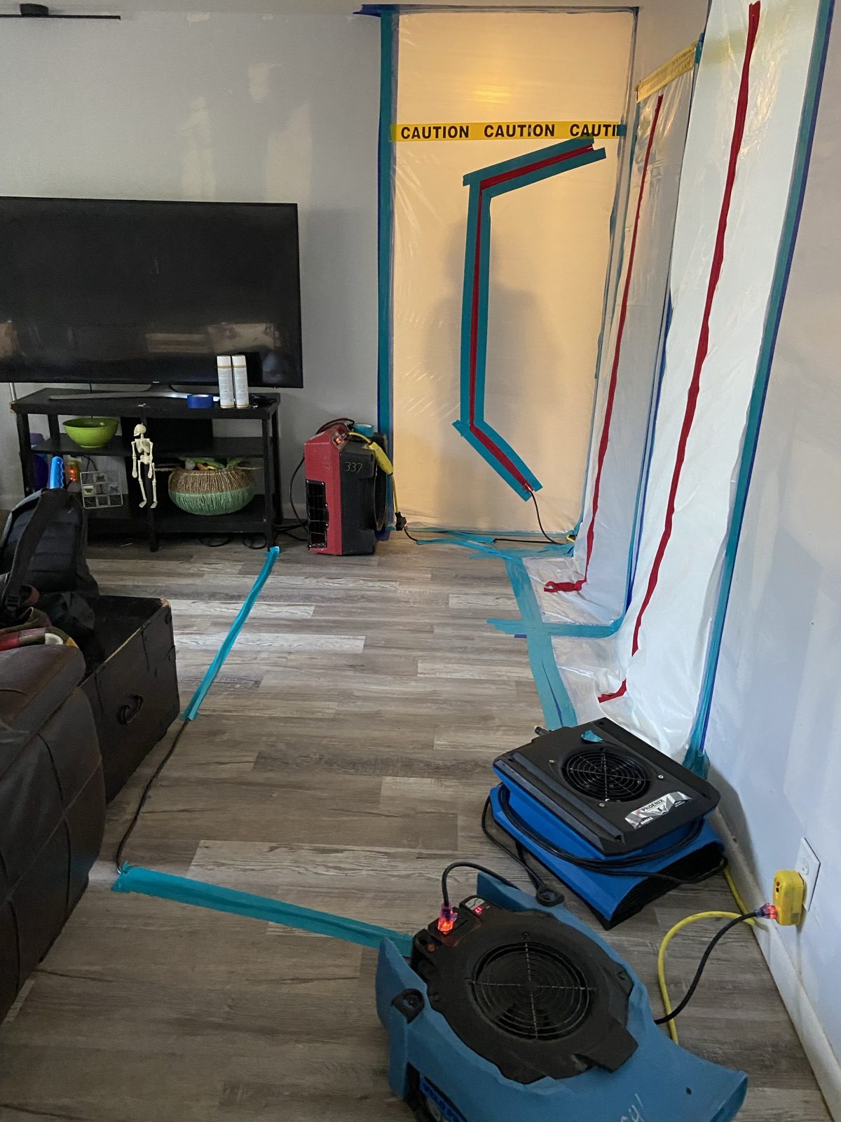 Air movers and dehumidifier drying a storm-flooded room under containment