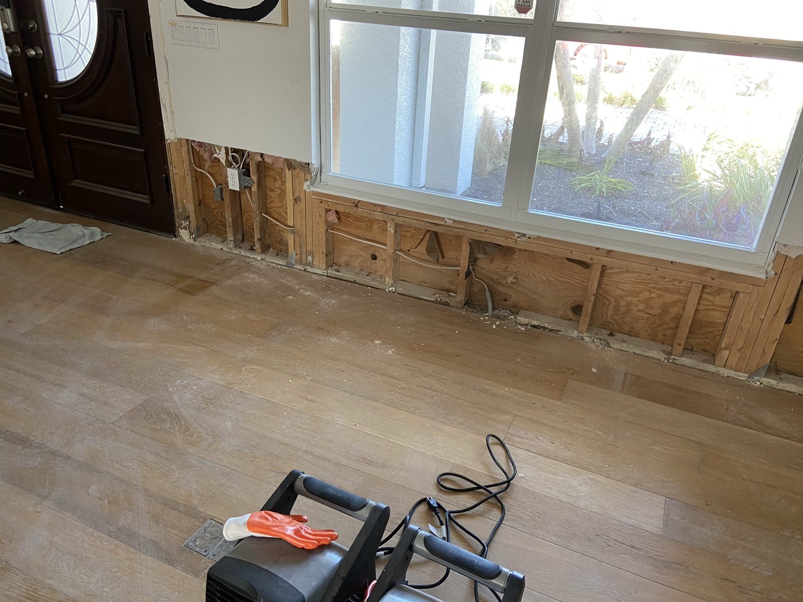 Flood cut along a wall with exposed framing and an air mover drying