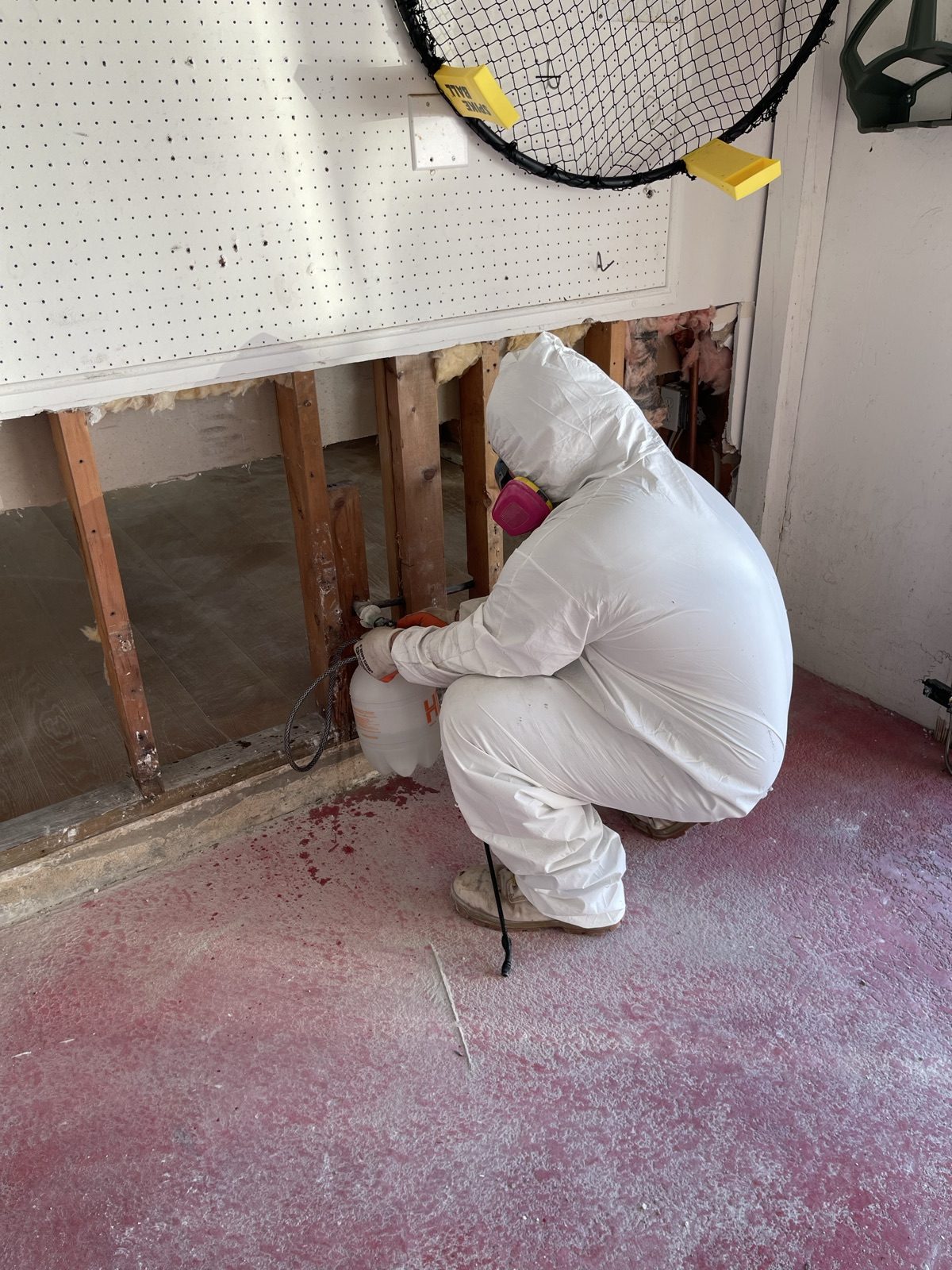 Technician in full PPE performing controlled demolition of damaged materials